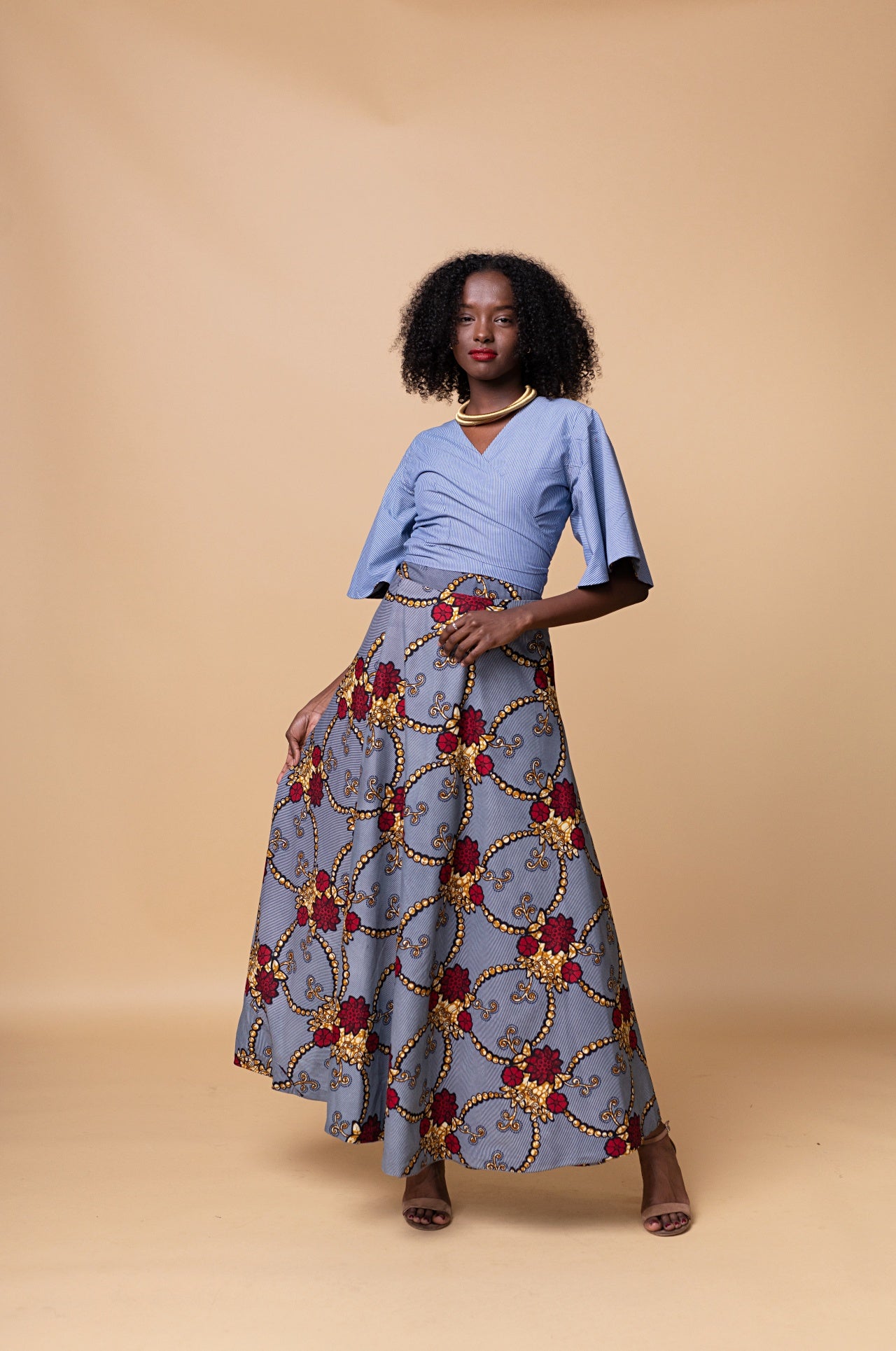 Model wearing Reversible Wrap Skirt – high-waisted maxi wrap skirt with floral African print one side and vibrant orange reverse, tie waist, Nigerian made.